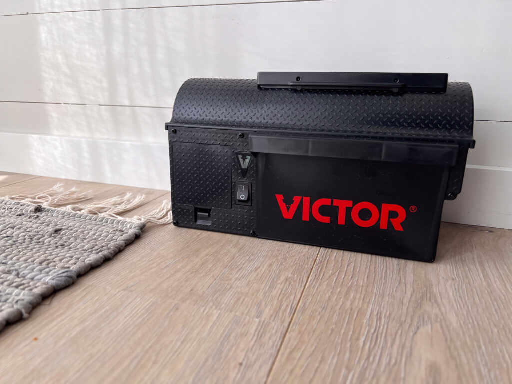 Victor Multi-Kill, på et tregulv, med et grått teppe ved siden av, opp mot en hvit panelvegg